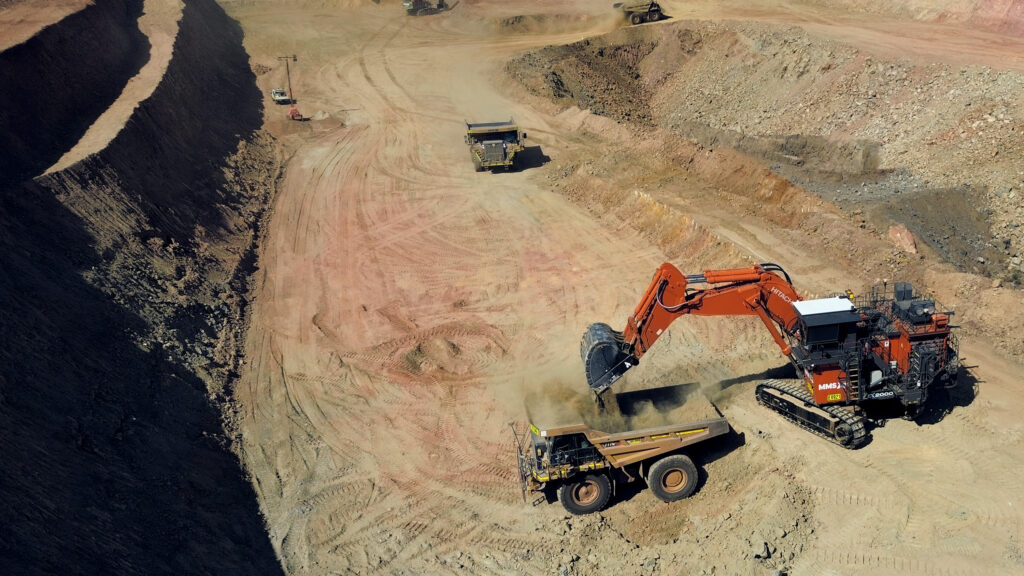 drone-shot-orange-excavator-unloading-dirt-onto-haul-truck