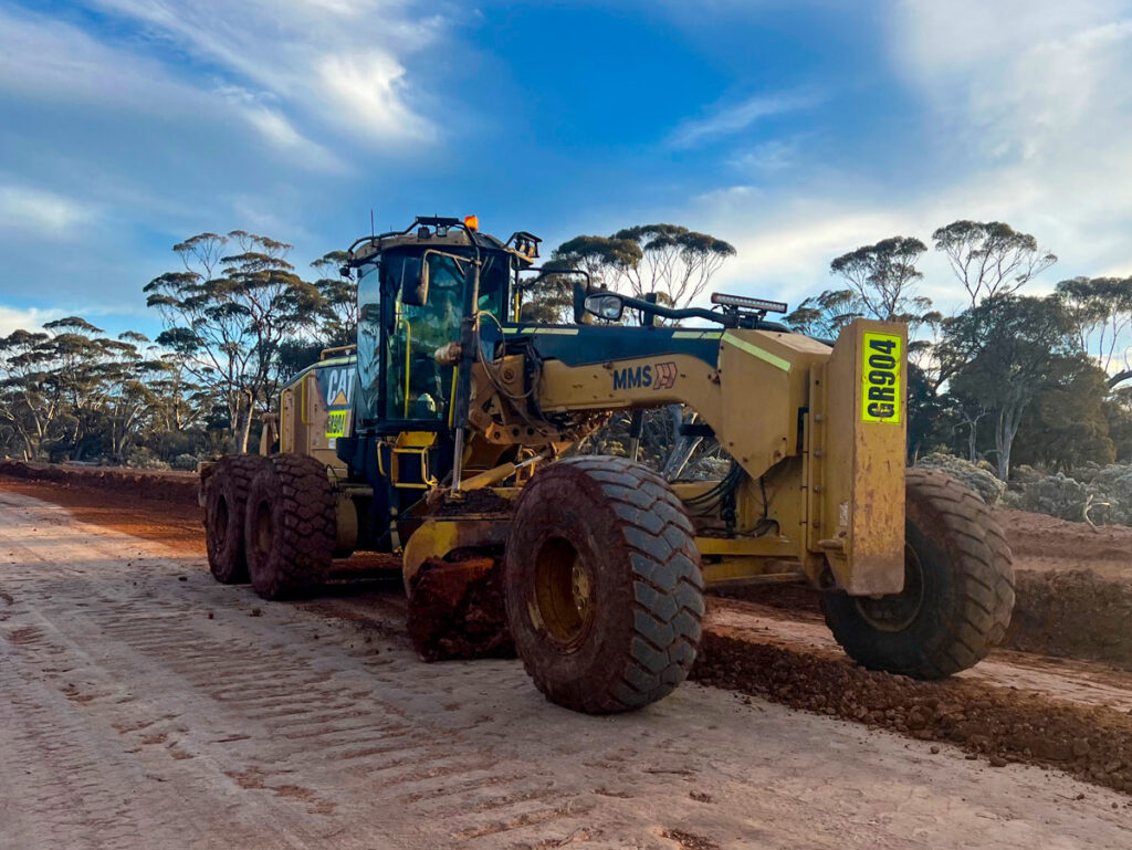 Grader-vehicle-travelling-across-desert-road