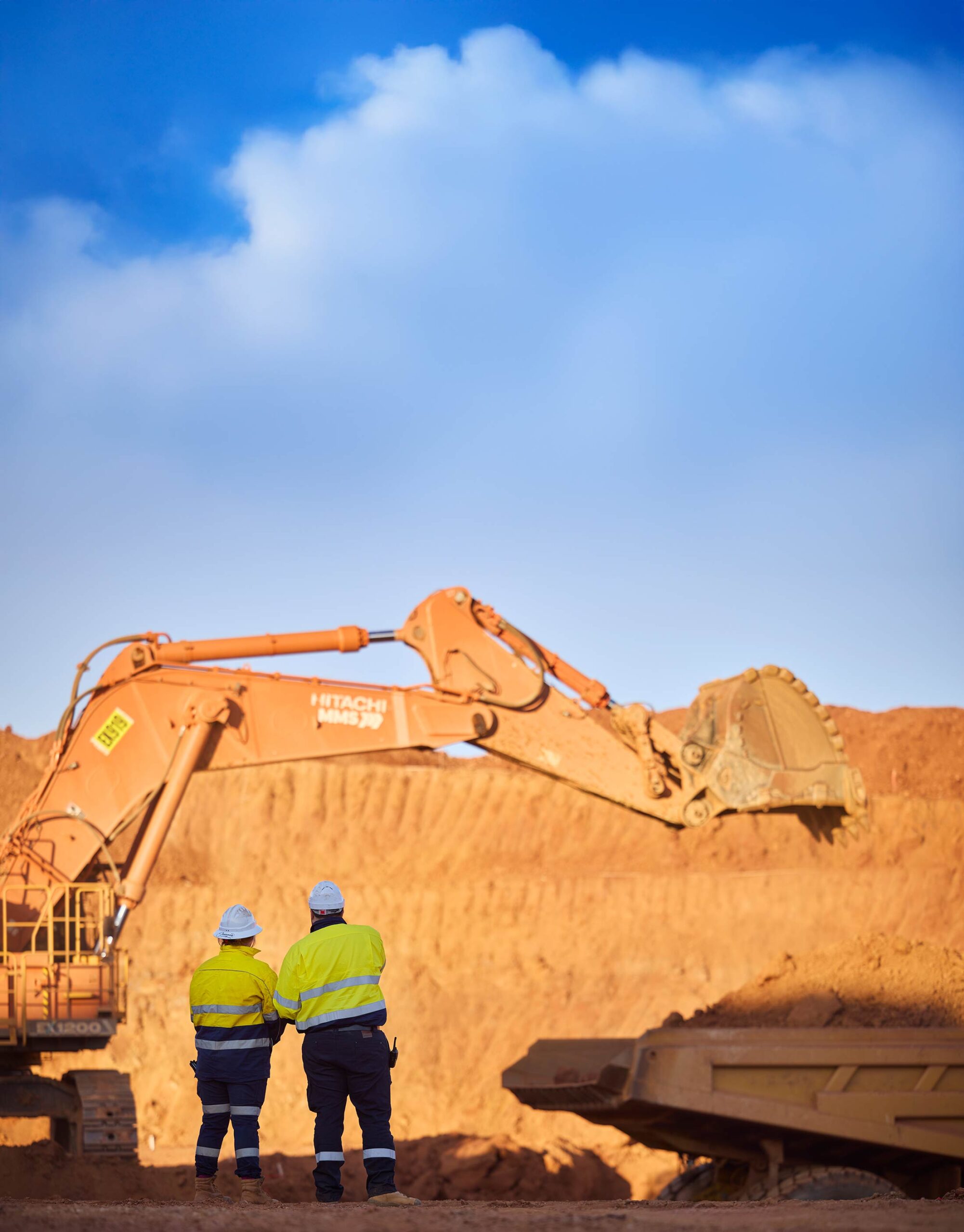 Two MMS heavy‑equipment operators in high‑visibility gear inspect a large excavator on a mine site in Western Australia.”